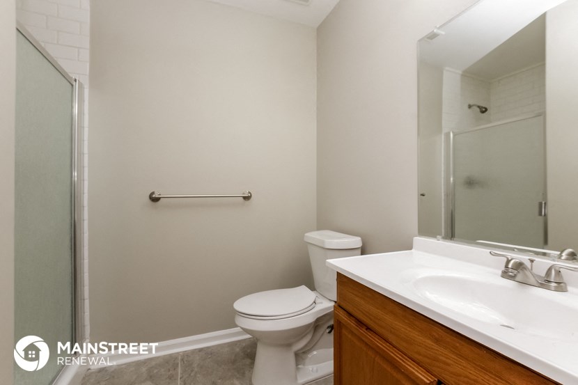 a bathroom with a toilet sink and mirror and a shower