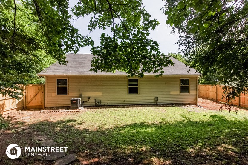 a small yellow house in a backyard with trees