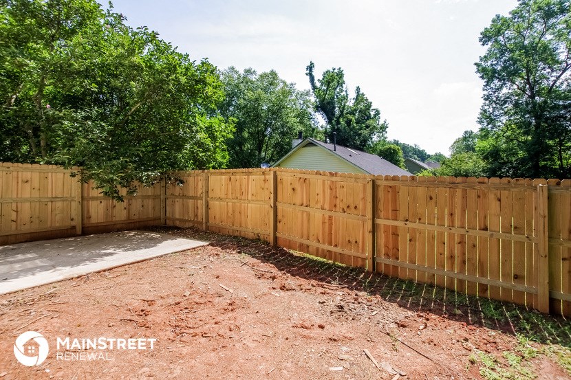 a wooden fence in front of a yard with dirt