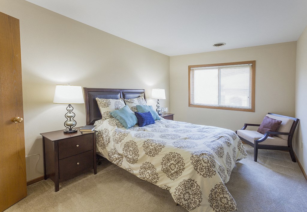 a bedroom with a bed and a chair and a window