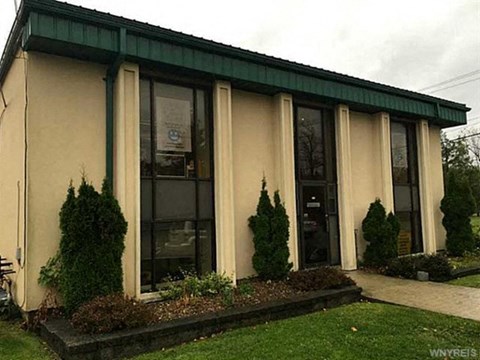the front of a building with windows and a green roof