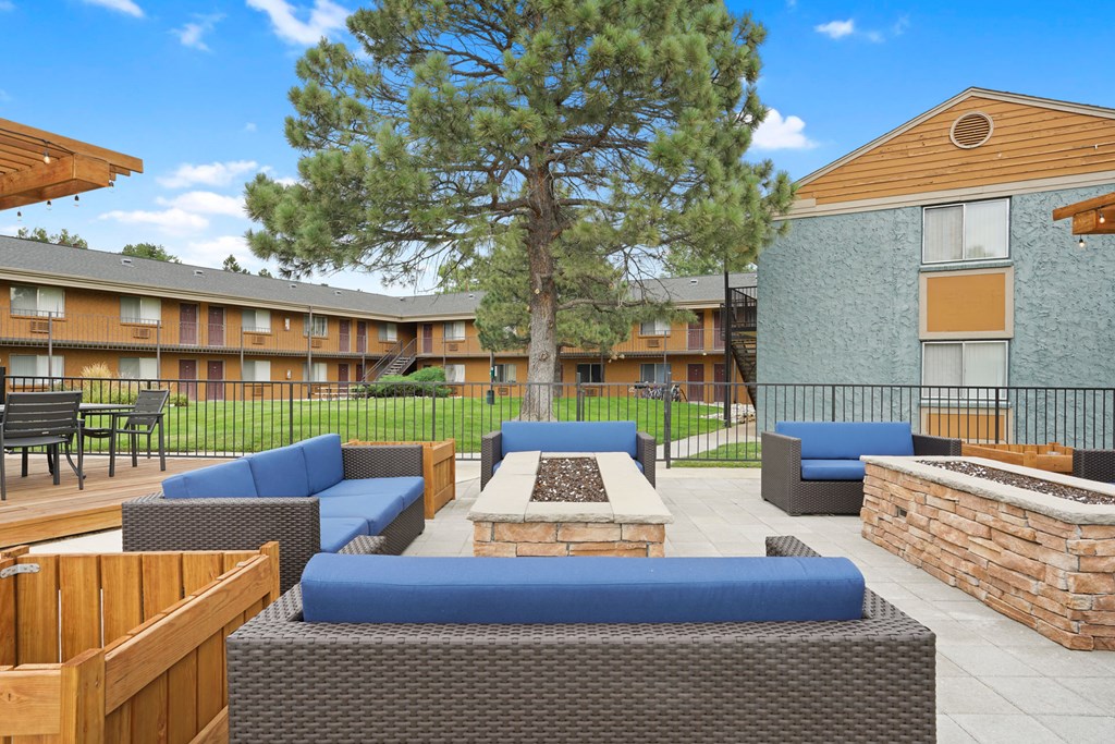 a patio with couches and a fire pit in front of a building
