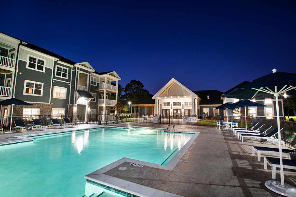 illuminated swimming pool at night with apartments in the evening