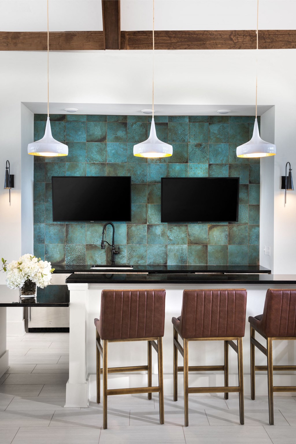 a kitchen with a bar and chairs and a television on the wall