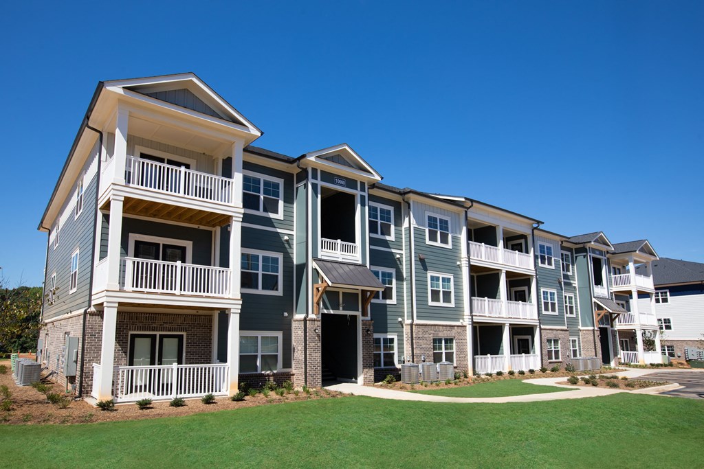 an apartment building with green grass in front of it