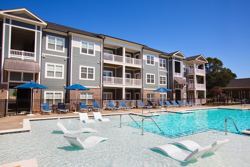 an apartment building with a swimming pool and blue umbrellas