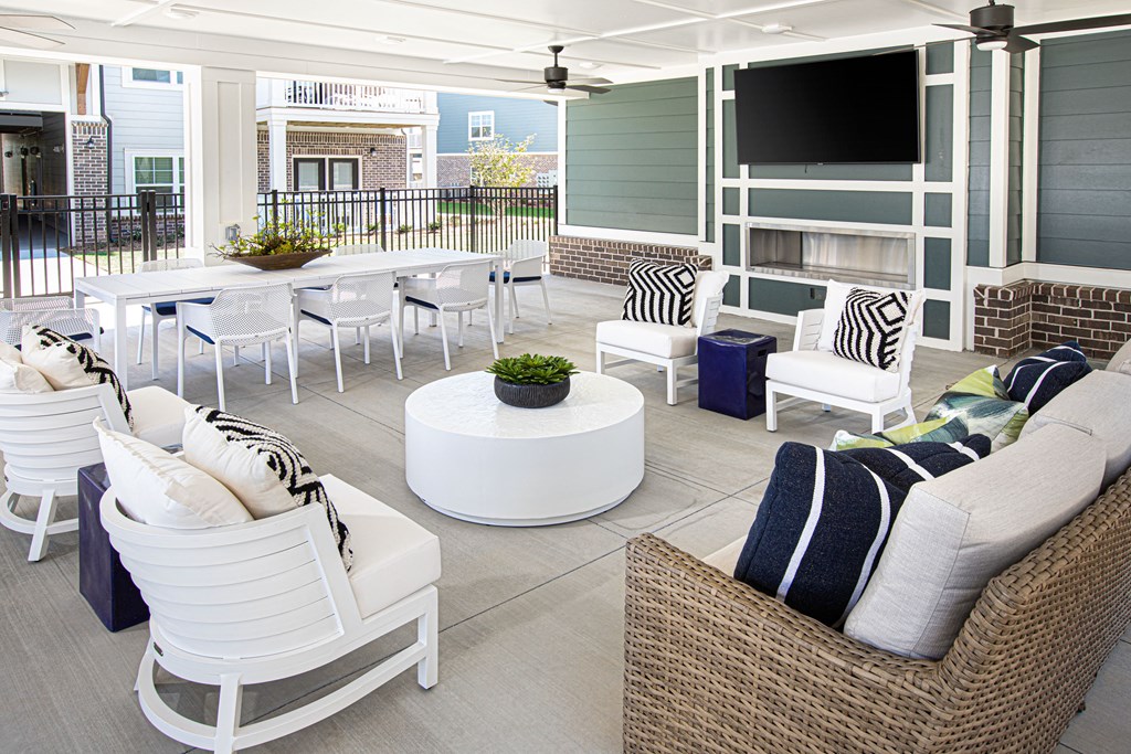 a living room with white chairs and tables and a television
