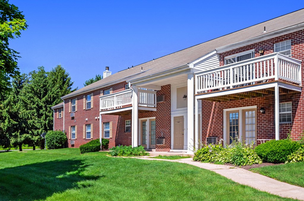 a brick building with a balcony and a lawn