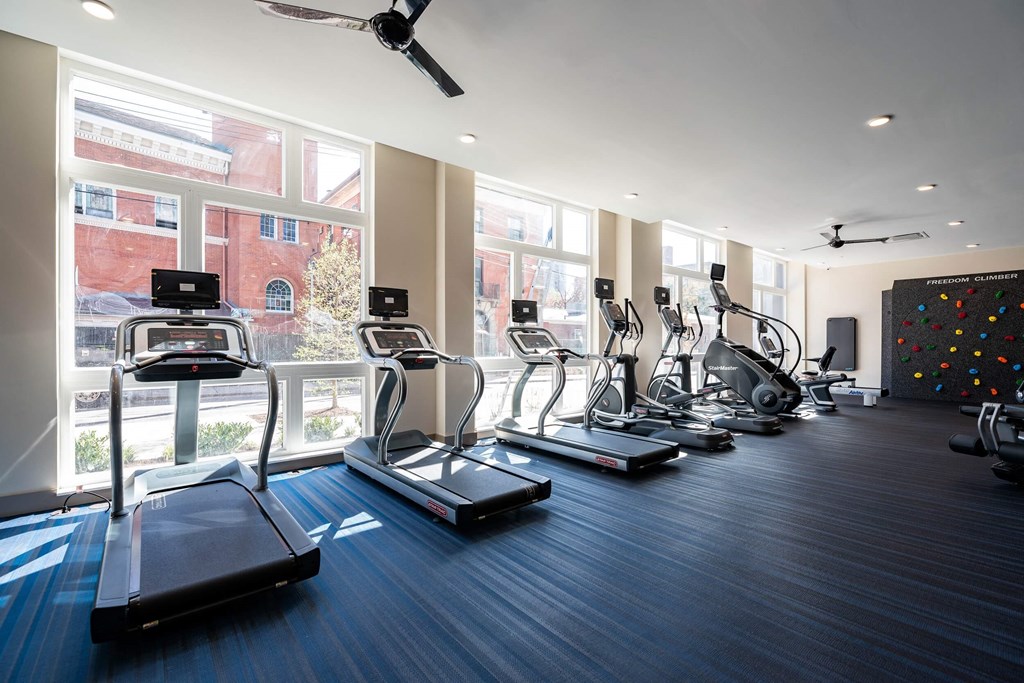 a gym with cardio equipment and windows in a building