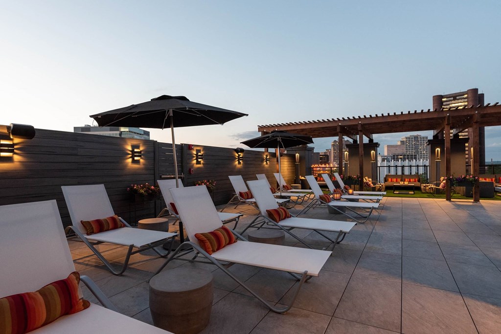 a row of lounge chairs on a roof top patio with umbrellas