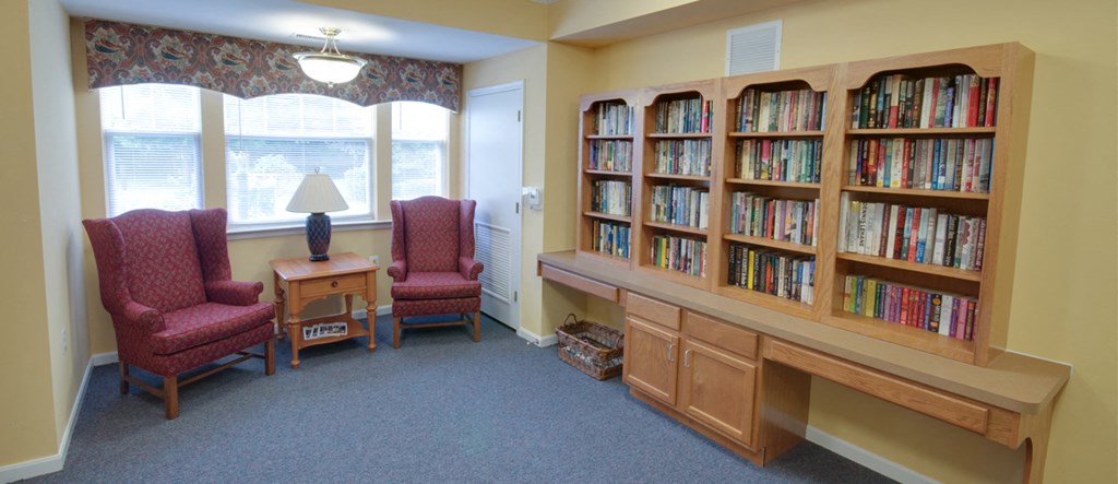 a library with chairs and a table and a book shelf