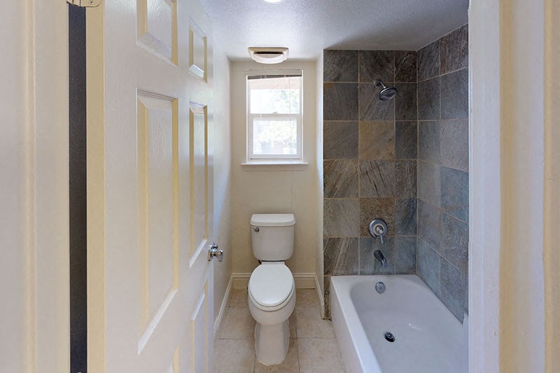 a bathroom with a toilet and a tub and a window