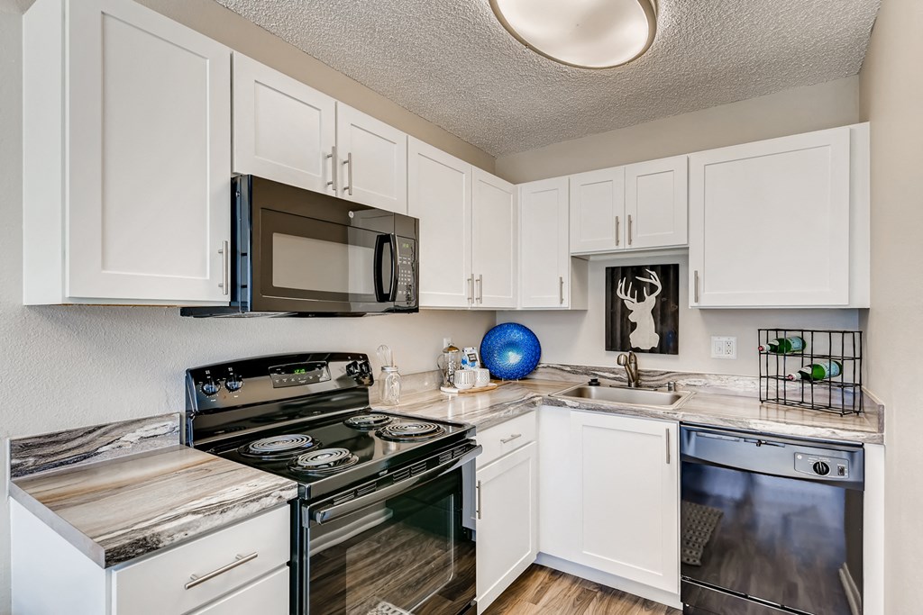 an updated kitchen with stainless steel appliances and white cabinets