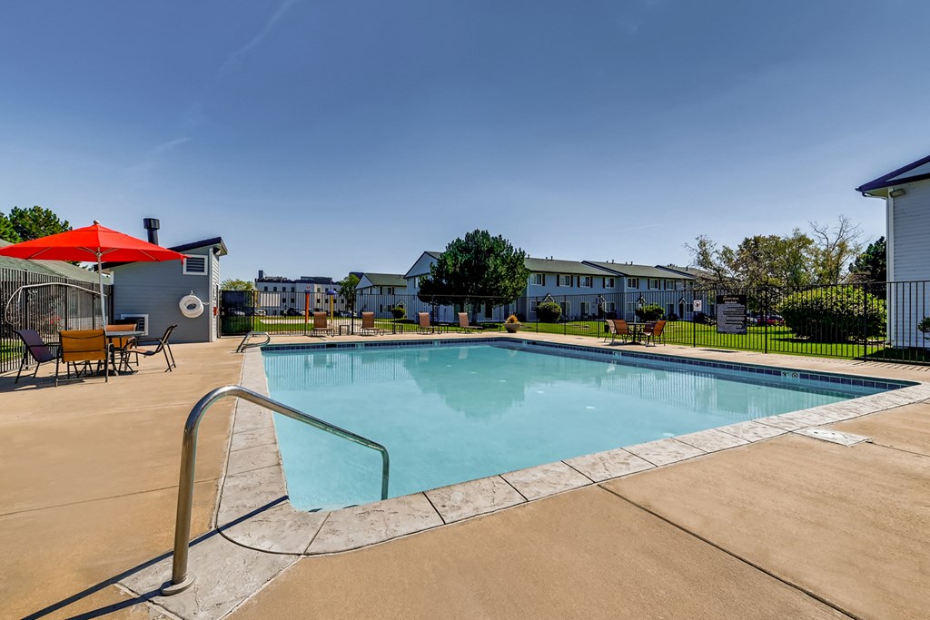our resort style swimming pool is surrounded by our apartments and has an umbrella and chairs