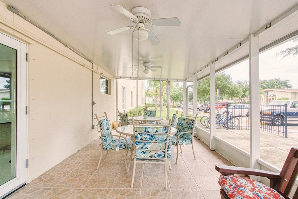 Patio with tables, chairs, and ceiling fans at Holy Cross Manor I