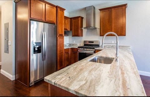 A kitchen with a stainless steel refrigerator and a marble countertop.
