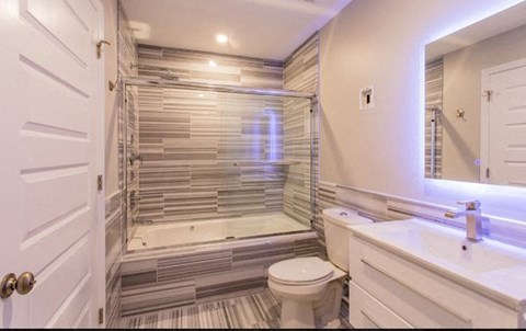 A white bathroom with a toilet, sink, and a walk-in shower.