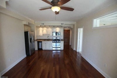 an empty living room and kitchen with a ceiling fan