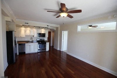an empty living room and kitchen with a ceiling fan