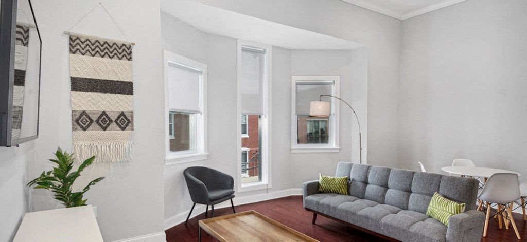 a living room with a couch and a table and three windows