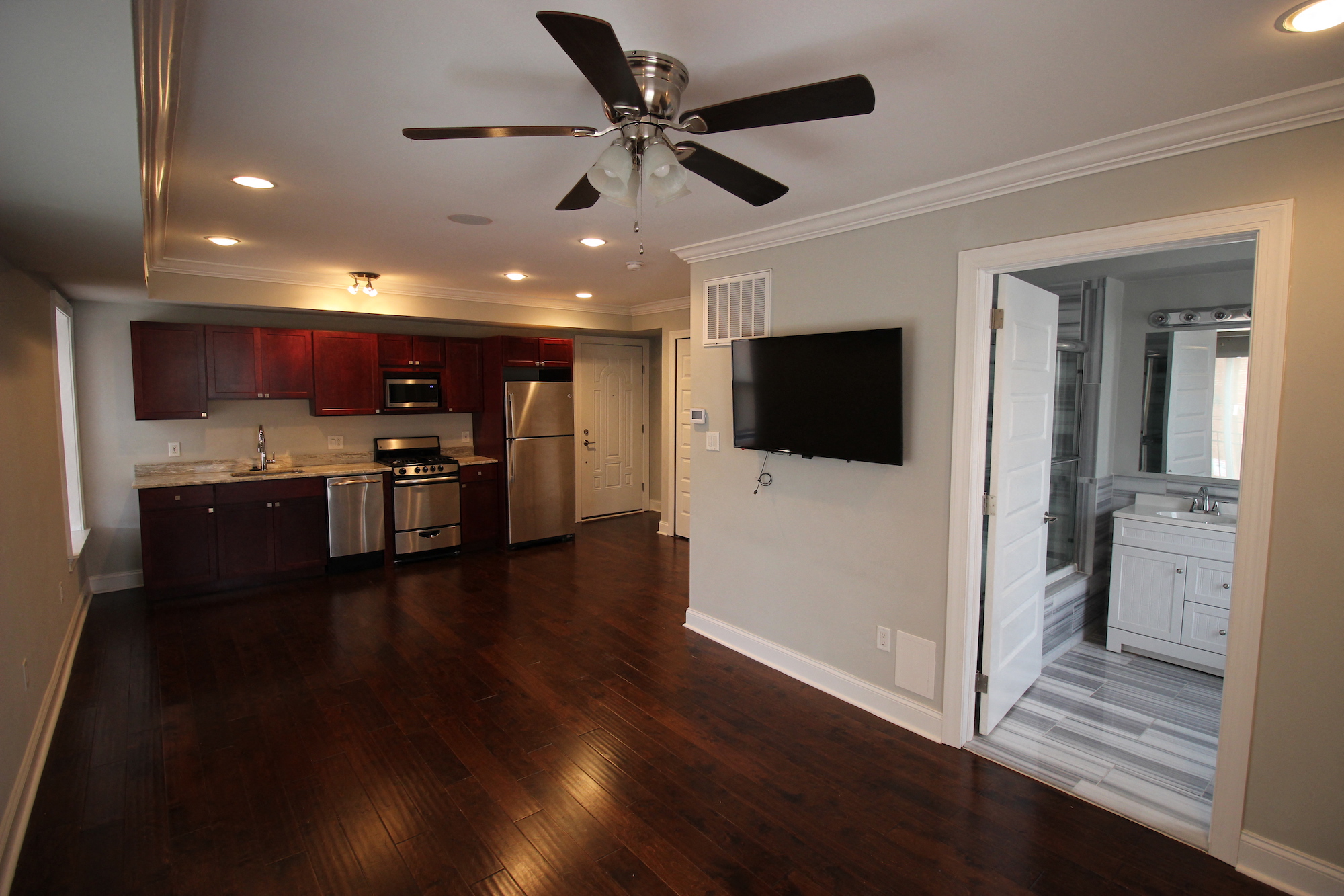 an empty living room with a ceiling fan and a kitchen