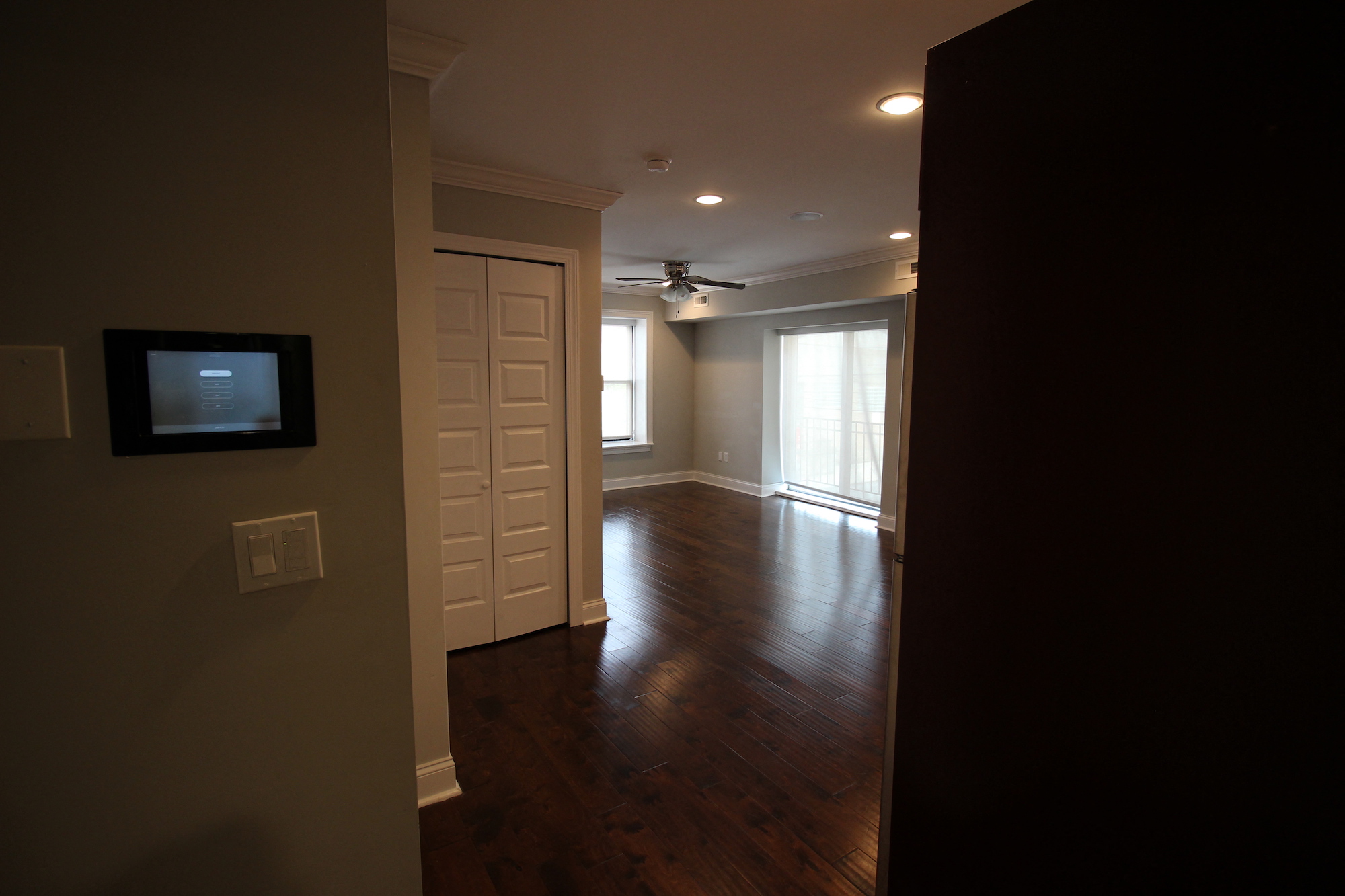an empty living room with wood floors and a ceiling fan
