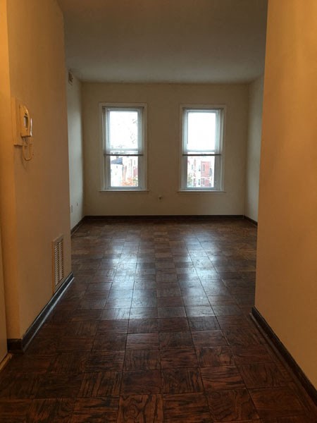 an empty living room with two windows and a tiled floor