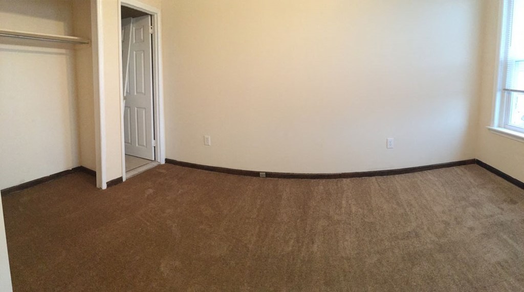 an empty living room with carpet and a door