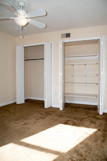 an empty bedroom with a closet and a ceiling fan