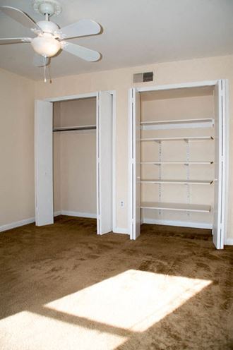 an empty bedroom with a closet and a ceiling fan