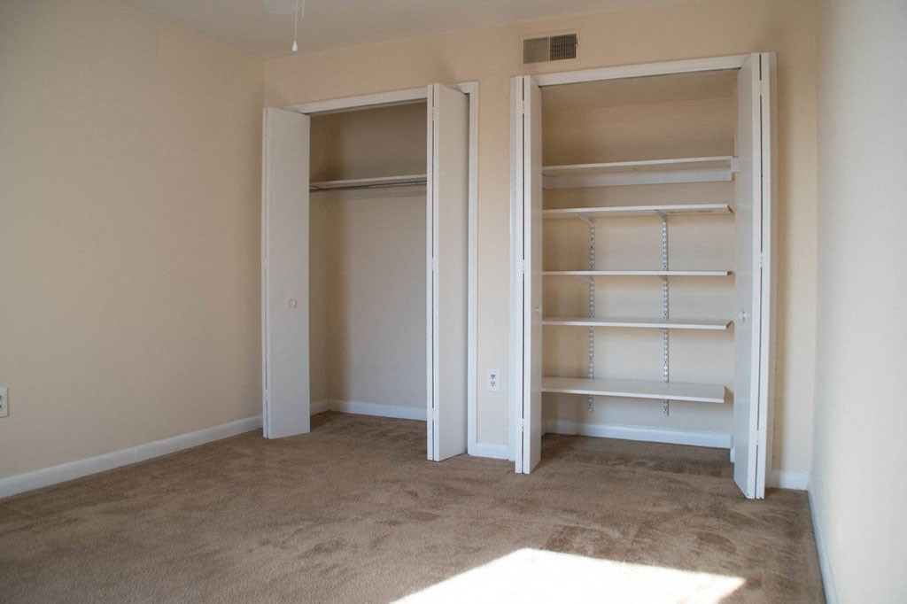 a bedroom with a closet and a carpeted floor