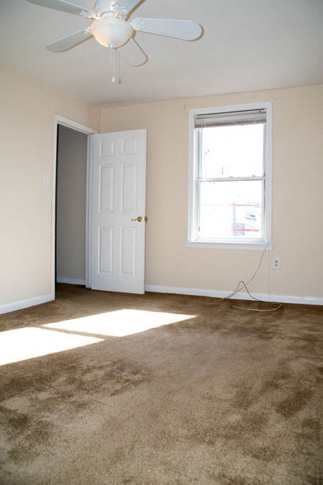 an empty living room with a ceiling fan and a window