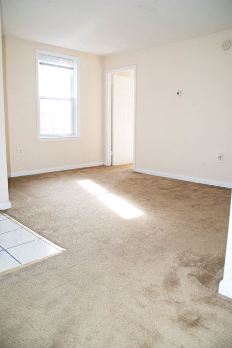 an empty living room with a carpeted floor and a window