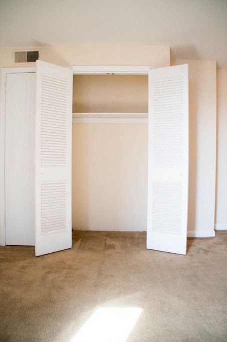 an empty room with two white shuttered closet doors