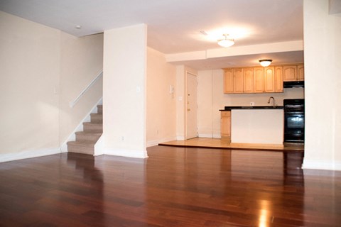 an empty living room with a staircase and a kitchen