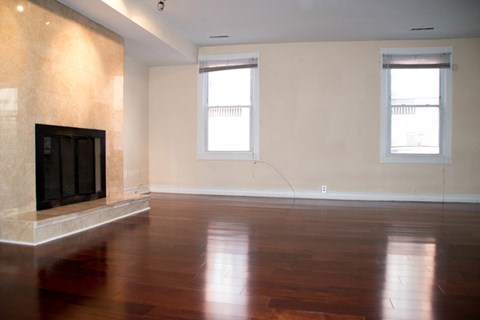 an empty living room with a fireplace and wooden floors