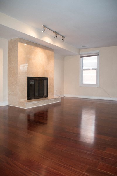 an empty living room with a fireplace and wooden floors