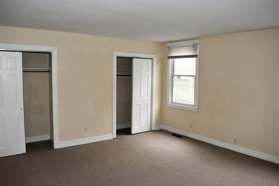 an empty living room with two closets and a window