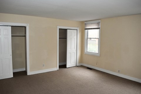 an empty living room with two closets and a window