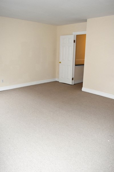 an empty living room with a door to a kitchen