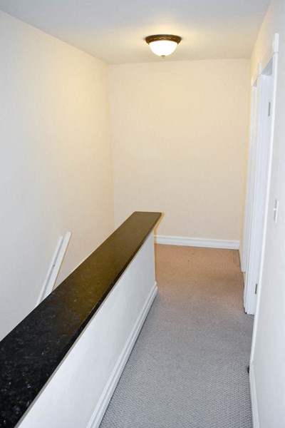 a hallway with a long counter top in a room with white walls and a light