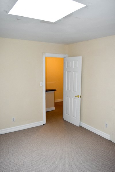 an empty room with a door open to a hallway with a desk and a door
