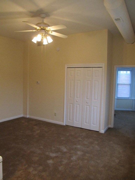 an empty living room with a ceiling fan and a door