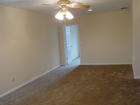 an empty living room with a ceiling fan