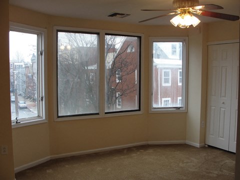 a living room with four windows and a ceiling fan