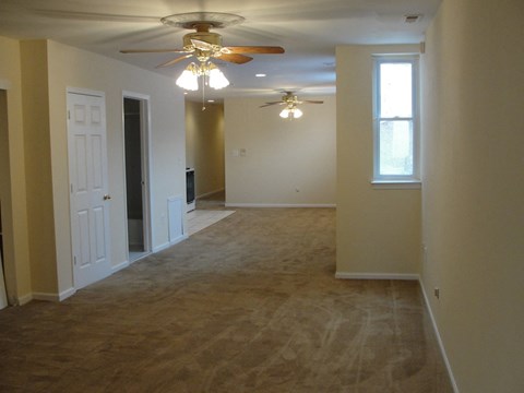an empty living room with a ceiling fan