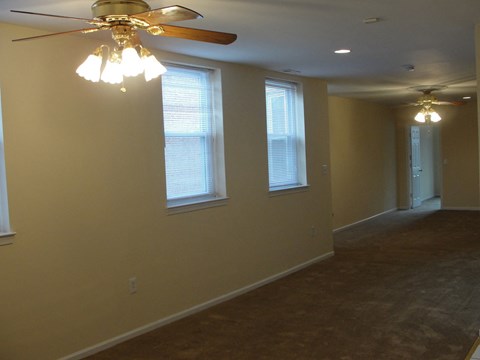 a living room with a ceiling fan and three windows