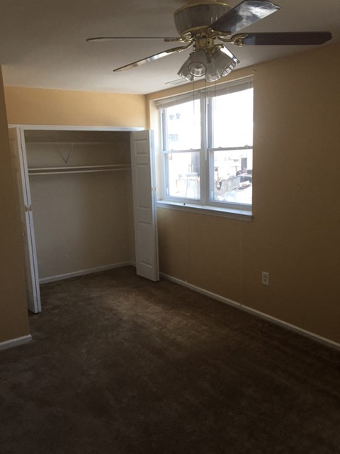 a bedroom with a ceiling fan and a closet