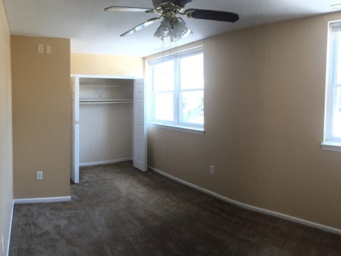 an empty living room with a ceiling fan and a closet
