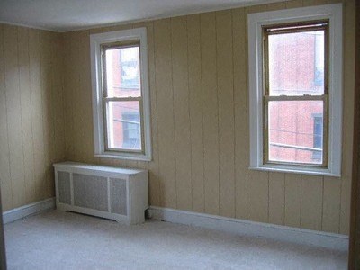 an empty room with a radiator and two windows